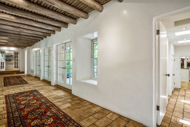 hallway featuring beam ceiling, french doors, and light tile floors