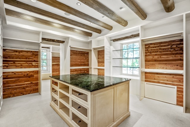 walk in closet with beam ceiling and light carpet