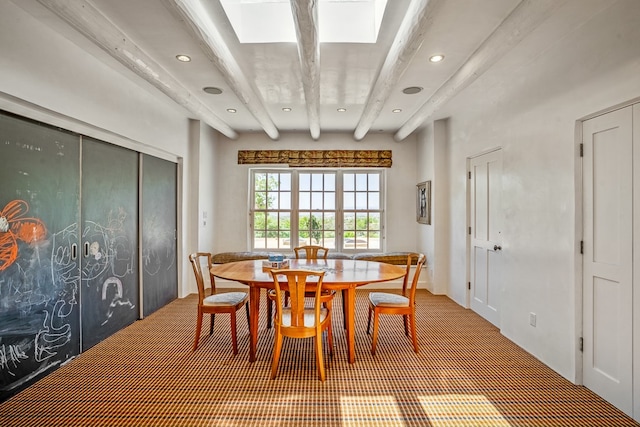 dining room with beamed ceiling and a skylight