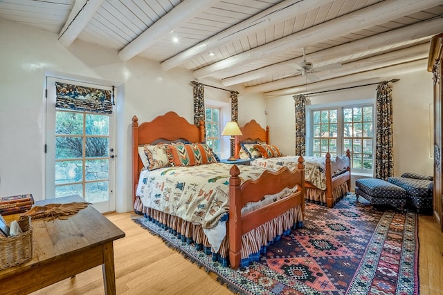 bedroom featuring beamed ceiling, multiple windows, and wood-type flooring