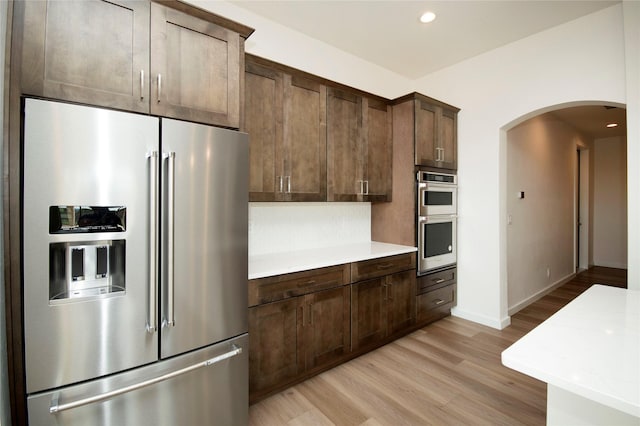 kitchen with dark brown cabinets, light hardwood / wood-style floors, and stainless steel appliances