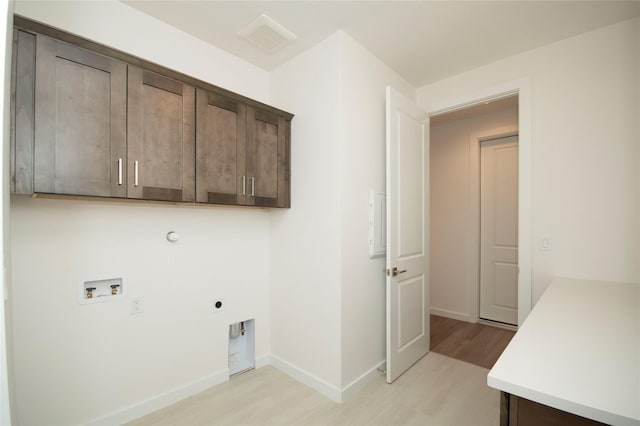 washroom with electric dryer hookup, hookup for a washing machine, light hardwood / wood-style flooring, and cabinets