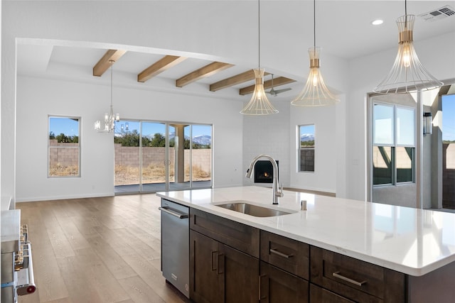 kitchen featuring beamed ceiling, light hardwood / wood-style flooring, a kitchen island with sink, and sink