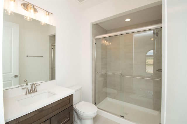 bathroom with vanity, toilet, and a shower with shower door