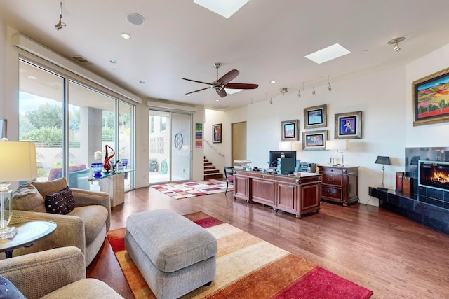 office space with rail lighting, ceiling fan, hardwood / wood-style flooring, and a tile fireplace