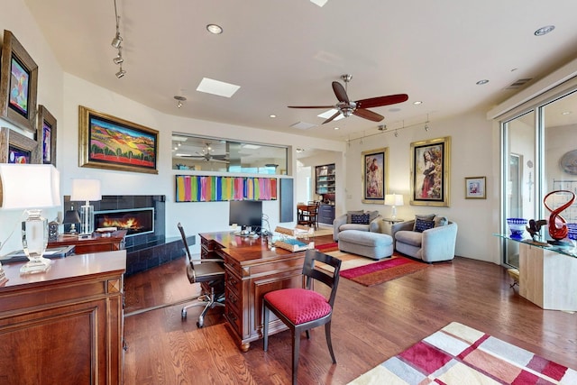 living room featuring ceiling fan, a fireplace, and dark hardwood / wood-style flooring