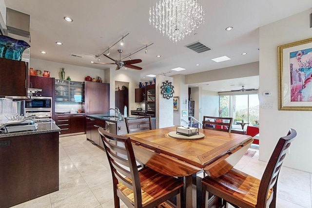 dining area with sink, ceiling fan with notable chandelier, and light tile patterned floors