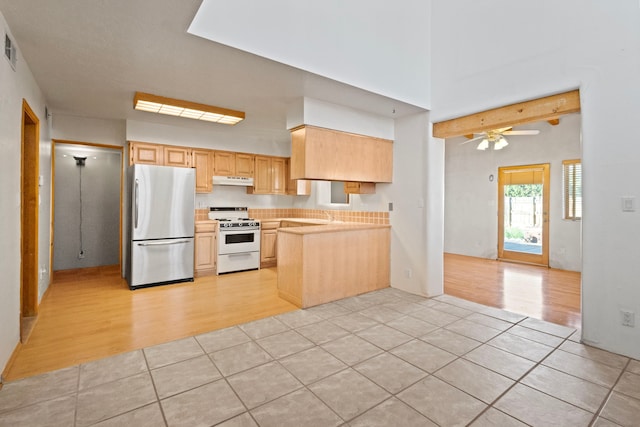 kitchen featuring gas range gas stove, stainless steel refrigerator, ceiling fan, and light tile floors