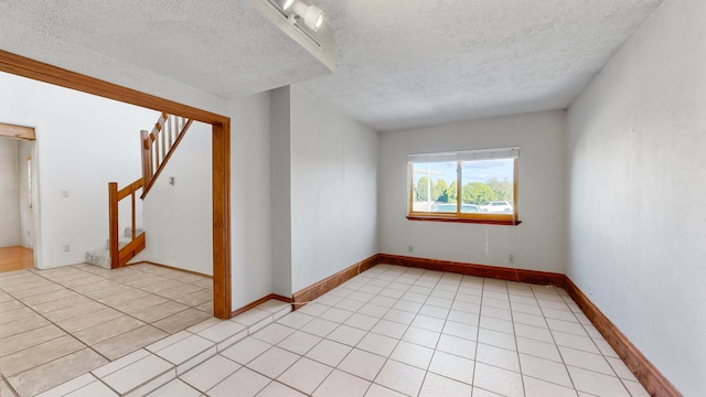 tiled spare room featuring a textured ceiling