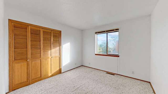 unfurnished bedroom with light colored carpet and a closet