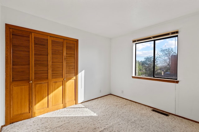 unfurnished bedroom featuring light carpet and a closet