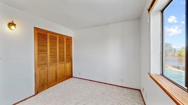 unfurnished bedroom featuring a closet and light carpet