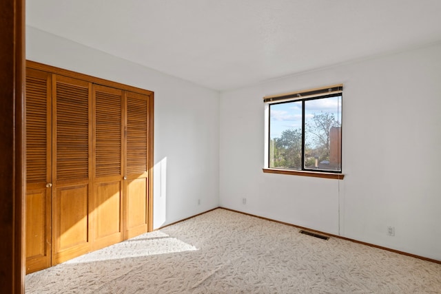 unfurnished bedroom with a closet and light carpet