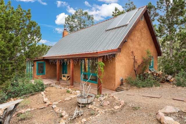 87 Quartz Trl, Santa Fe, NM 87505 - chalet / cabin featuring stucco siding, a chimney, metal roof, and a patio