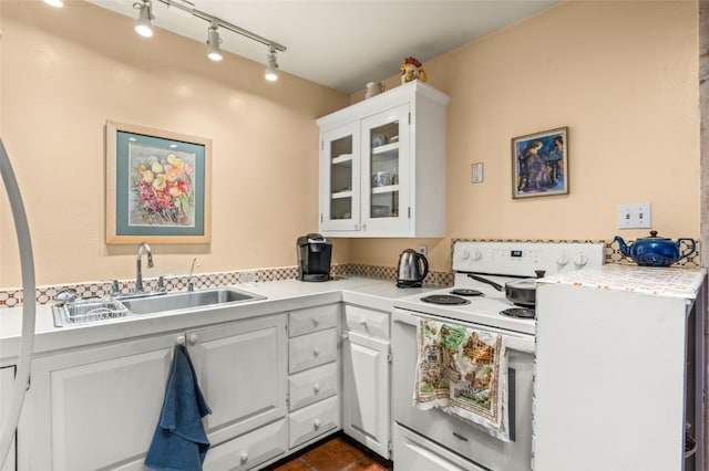 kitchen featuring white range with electric stovetop, rail lighting, dark tile flooring, sink, and white cabinetry