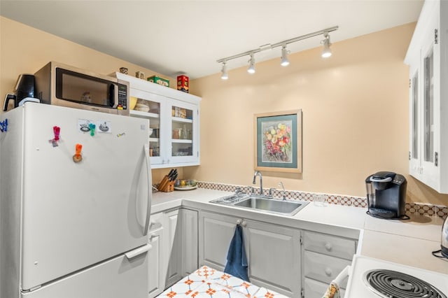 kitchen with white cabinetry, sink, white fridge, and track lighting