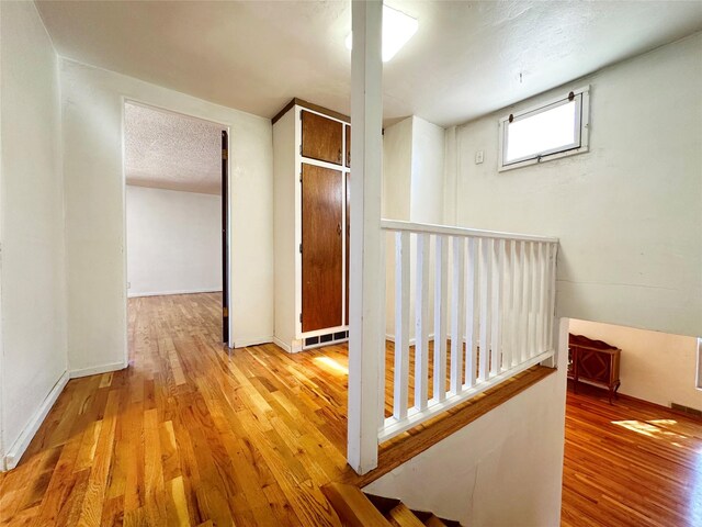 hallway with a textured ceiling and hardwood / wood-style floors