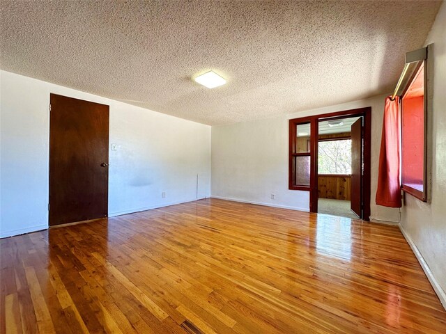 spare room featuring wood-type flooring and a textured ceiling