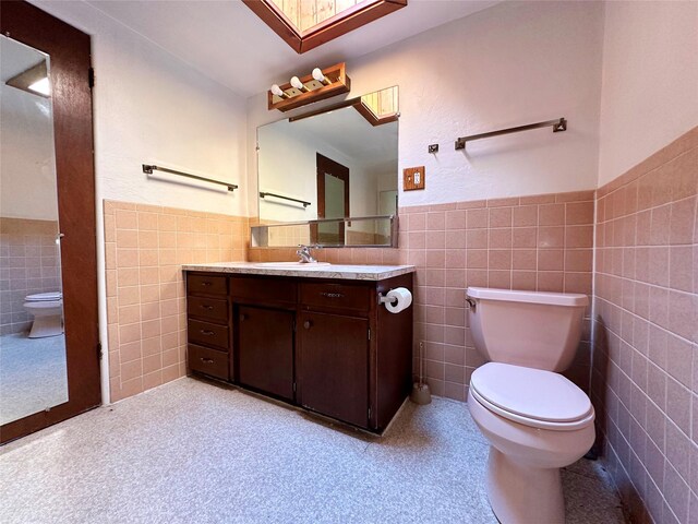 bathroom featuring tile walls, tile flooring, vanity, and toilet