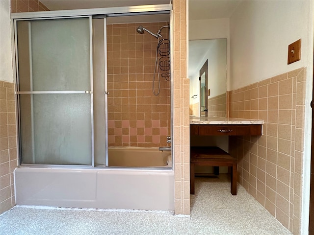 bathroom featuring combined bath / shower with glass door and tile walls