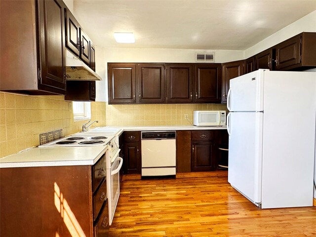 kitchen featuring light hardwood / wood-style floors, white appliances, wall chimney range hood, and tasteful backsplash