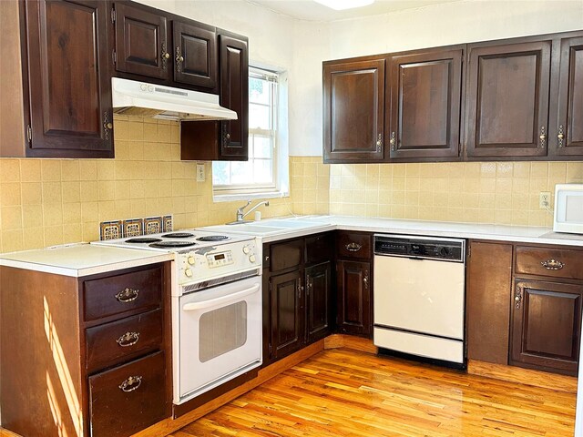 kitchen featuring backsplash, sink, white appliances, and light hardwood / wood-style flooring