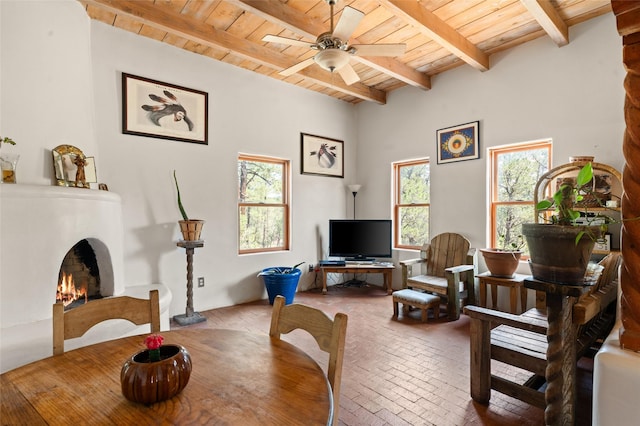 living area featuring ceiling fan, wood ceiling, and beamed ceiling