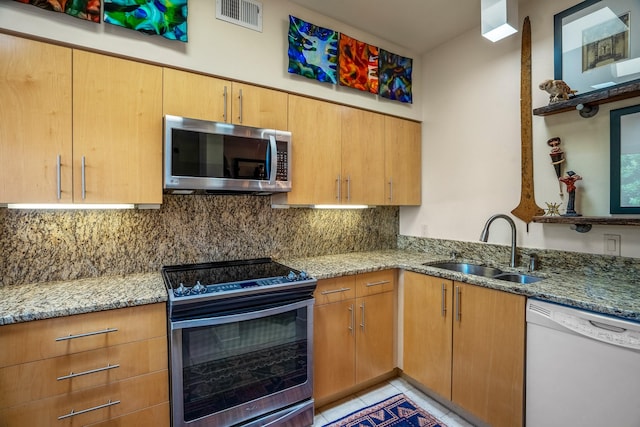 kitchen featuring sink, light tile patterned floors, stainless steel appliances, light stone counters, and decorative backsplash