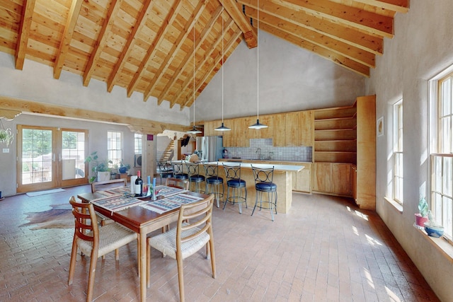 dining area with french doors, sink, high vaulted ceiling, and beam ceiling