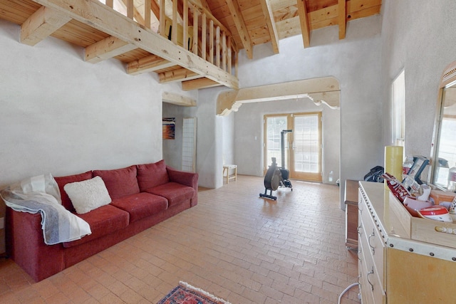 living room with a towering ceiling, beamed ceiling, and wood ceiling