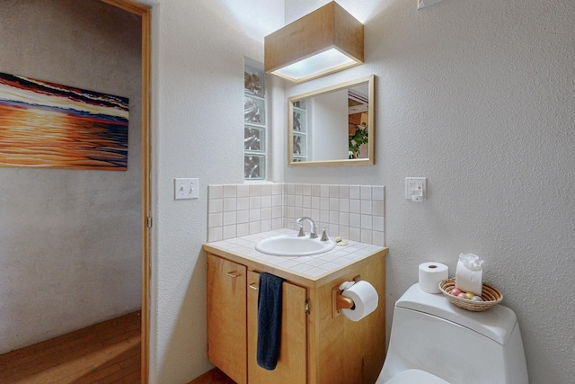 bathroom featuring decorative backsplash, toilet, and vanity