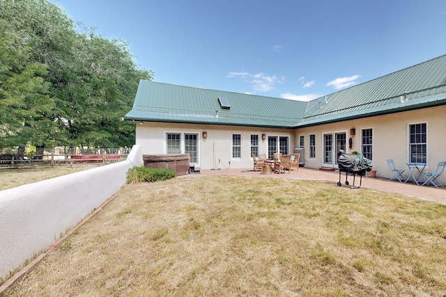 rear view of property featuring a lawn, a patio, and a hot tub