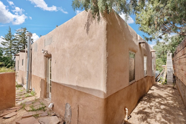 view of side of property with fence and stucco siding