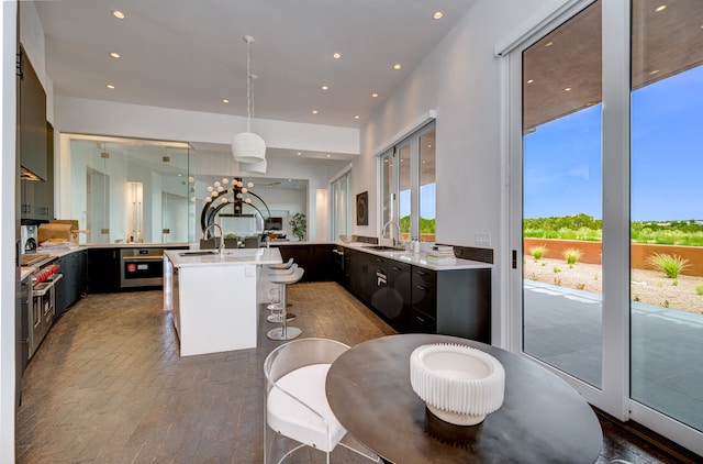 kitchen featuring sink, pendant lighting, an island with sink, and oven