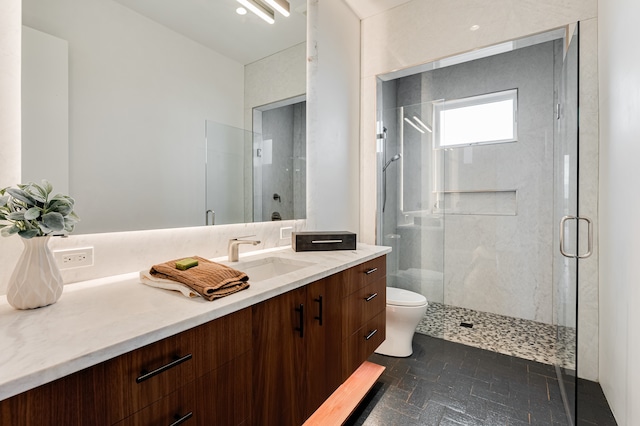 bathroom with a shower with door, vanity, tile patterned floors, and toilet