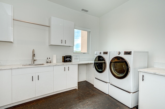 washroom with cabinets, washing machine and dryer, and sink