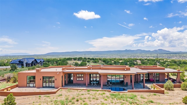 back of property featuring a mountain view and a patio area