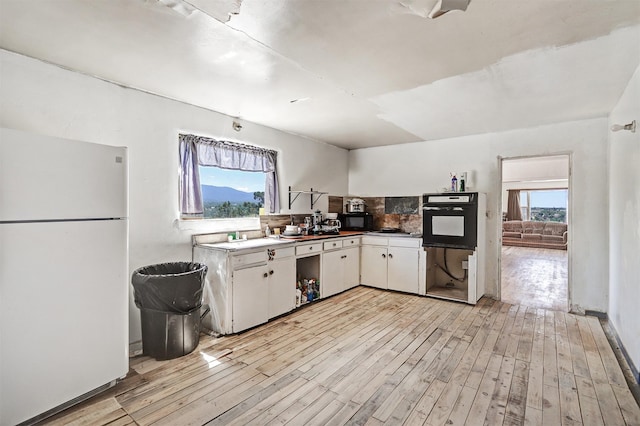 kitchen featuring sink, backsplash, white cabinets, light hardwood / wood-style floors, and black appliances