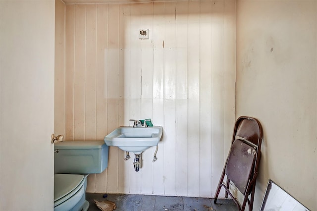 bathroom with toilet and wood walls