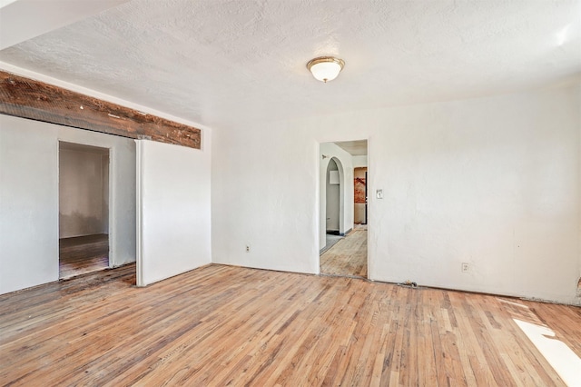 spare room with a textured ceiling and light wood-type flooring