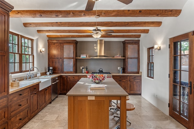 kitchen featuring stainless steel microwave, a kitchen island, light brown cabinets, beamed ceiling, and ceiling fan