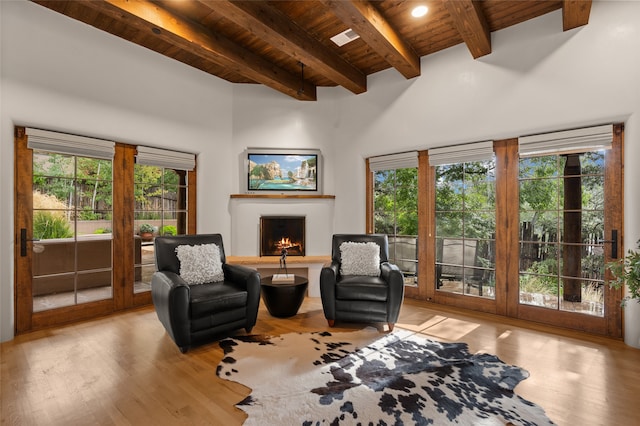 living room with beamed ceiling, light wood-type flooring, plenty of natural light, and wooden ceiling