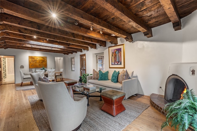 living room with wood ceiling, a brick fireplace, beamed ceiling, and plenty of natural light