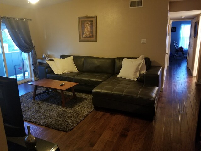 living room with plenty of natural light and dark wood-type flooring