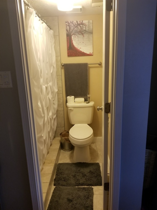 bathroom featuring toilet, a shower with curtain, and tile patterned floors