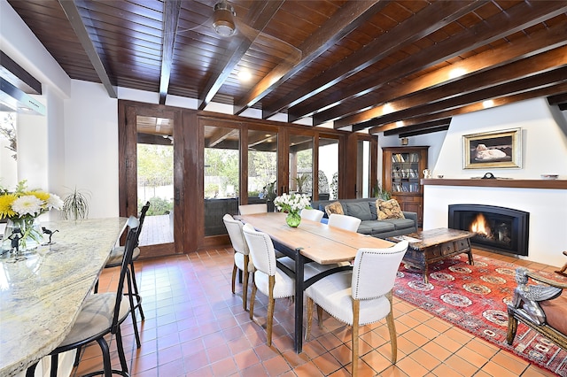 dining space with beamed ceiling, a large fireplace, tile patterned flooring, and wood ceiling