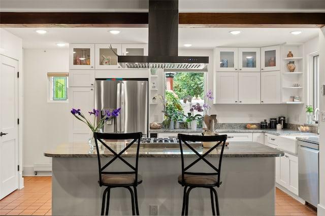 kitchen featuring white cabinetry, dark stone countertops, appliances with stainless steel finishes, a kitchen island, and island exhaust hood