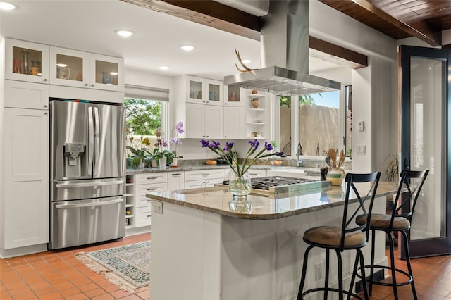 kitchen with a kitchen bar, white cabinetry, light stone counters, island range hood, and stainless steel appliances