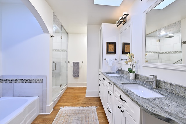 bathroom featuring a skylight, vanity, separate shower and tub, and hardwood / wood-style floors