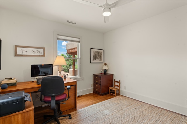 home office with light hardwood / wood-style floors, ceiling fan, and baseboard heating